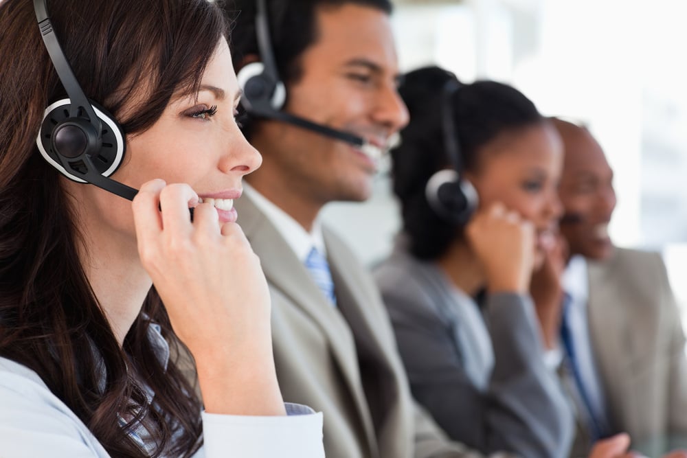 Young employee working with a headset and accompanied by her team-1